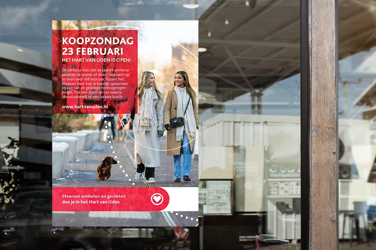 Een flyer aan de binnenkant van een winkelruit waarop geadverteerd wordt voor de koopzondag op 23 februari. Hierop staat twee vrouwen met een hond.