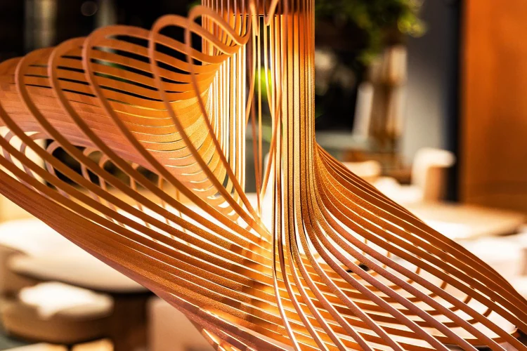 Close-up van een stijlvolle, gedetailleerde designlamp met goudkleurige metalen lijnen in een warme interieursetting.